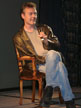 Anthony Head on a chair on stage