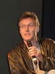 Anthony Head on a chair on stage