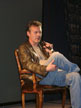 Anthony Head on a chair on stage