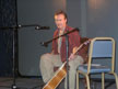 Anthony Head on stage with guitar (red shirt)