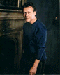 Tony in blue, standing in front of fireplace